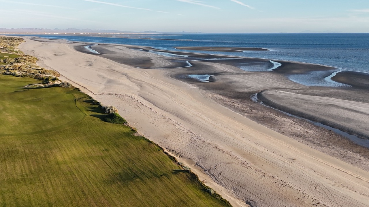 Aerial of the beach and low-tide sand flats beside a seaside golf course, Puerto Peñasco